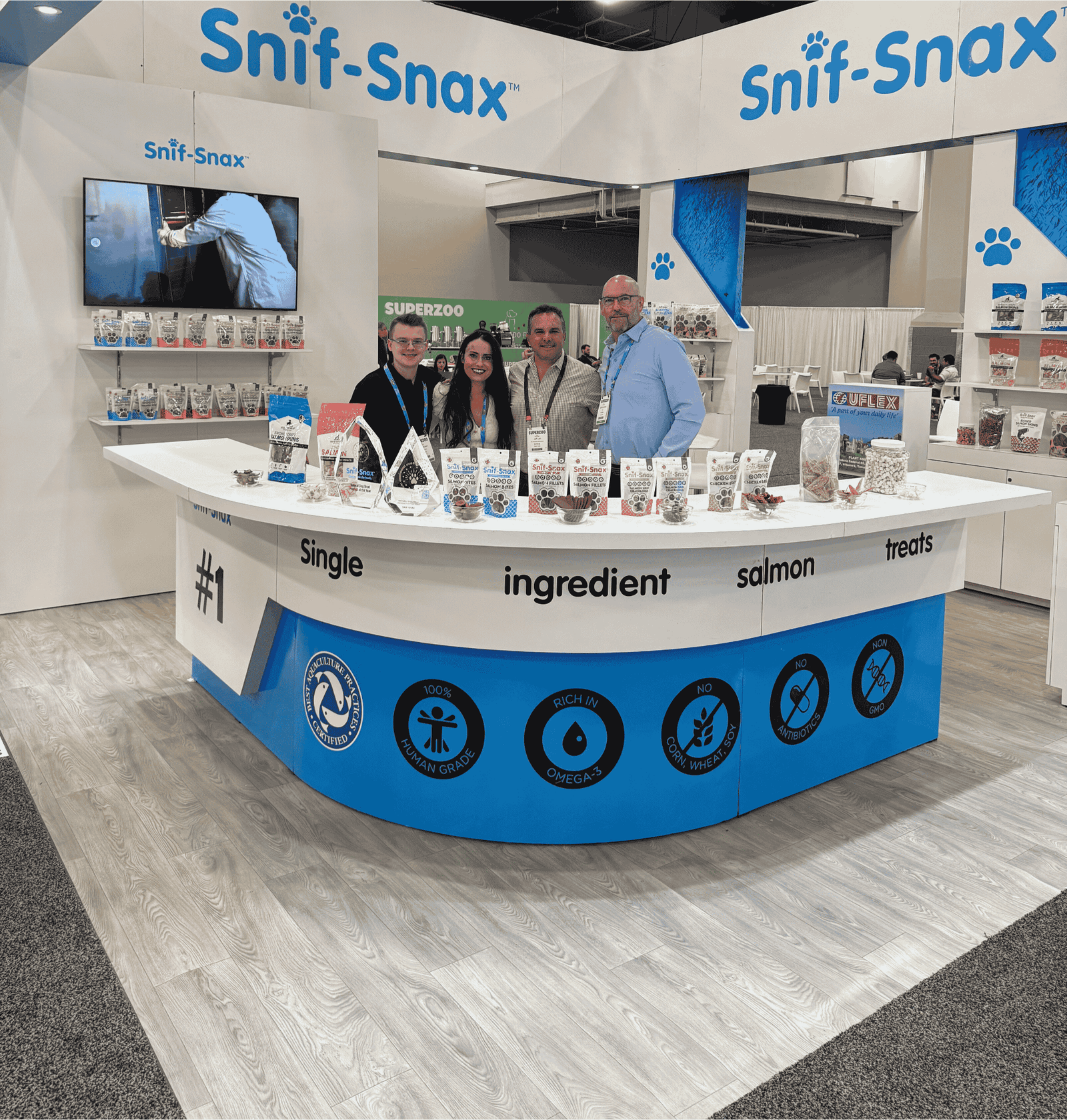 Snif-Snax booth with people around a display table at an event.